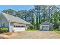 A two car garage with a detached garage and a paved driveway surrounded by lush greenery and trees at 230 Acorn Ct, Mcdonough, GA 30253