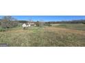 Scenic view of a charming home with dormer windows, surrounded by fields and a tree line at 1761 Reavesville Rd, Bowdon, GA 30108