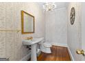 Traditional half bath with pedestal sink, gold fixtures, and decorative wallpaper at 180 Habersham Pl, Fayetteville, GA 30214