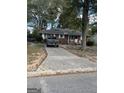 Charming brick home with a long driveway, mature trees and a quaint front porch at 6842 E Sherwood Dr, Riverdale, GA 30274