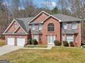 Charming two-story brick home with a two-car garage, manicured lawn, and beautiful landscaping at 204 Eleanor Ct, Stockbridge, GA 30281