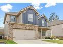 Charming home features a two-car garage, brick accents, and a well-manicured lawn at 312 Maddi Grace Ct, Locust Grove, GA 30248