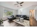Cozy living room with dark wood floors, large windows, ceiling fan, and ample seating at 4605 Woodcroft Cv, Snellville, GA 30039