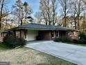 Brick home with carport and a wide driveway, surrounded by mature trees on a well-kept lawn at 398 Lockridge Ln, Lawrenceville, GA 30046