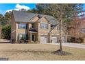 Traditional brick home with a three-car garage and a well-manicured front lawn with mature trees at 2441 Noelle Ln, Powder Springs, GA 30127