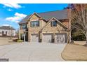 Traditional brick home with a three-car garage and a well-manicured front lawn on a sunny day at 2441 Noelle Ln, Powder Springs, GA 30127