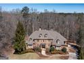 Aerial view of a brick two-story home with dormer windows, a large roof, and mature trees surrounding the property at 120 Kettering Trce, Tyrone, GA 30290