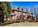 A brick two-story home with shuttered windows, a manicured lawn, and lush landscaping in the front yard at 120 Kettering Trce, Tyrone, GA 30290