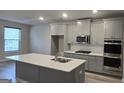Modern kitchen features an island, stainless steel appliances, and gray cabinetry at 336 Traditions Ln # 147, Hampton, GA 30228