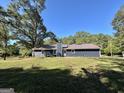 Rear view of a home with a chimney and a spacious backyard surrounded by lush trees at 3280 Gum Creek Rd, Oxford, GA 30054