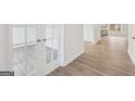 Bright, open-concept room with glass panel french doors, hardwood floor, and view to the kitchen at 3725 Heron Creek Ct, Loganville, GA 30052