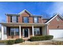 Beautiful brick home featuring a covered porch, black shutters, and green foundation shrubs at 7491 Hilltop Way, Atlanta, GA 30349