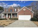 Traditional brick home with a two-car garage, inviting front porch, and well-kept lawn at 7491 Hilltop Way, Atlanta, GA 30349