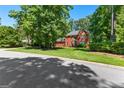Traditional brick home with a well-kept lawn, trees, and a glimpse of a neighbor's house, offering curb appeal at 423 Holly Grove Church Rd, Peachtree City, GA 30269