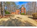 Traditional red brick home with a well-manicured lawn and mature trees in a suburban setting at 423 Holly Grove Church Rd, Peachtree City, GA 30269