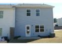 Back exterior featuring light blue siding, windows, and a small patio area with minimal landscaping at 7484 Knoll Hollow Rd, Lithonia, GA 30058