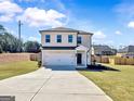 Two-story home featuring a brick exterior, attached two-car garage, and well-manicured front lawn at 301 Amsterdam Way, Hampton, GA 30228