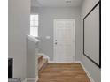 Bright foyer with hardwood floors, leading to a staircase and featuring a white front door at 301 Amsterdam Way, Hampton, GA 30228