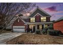 Charming two-story brick home at dusk with a well-manicured front yard and attached two-car garage in a quiet neighborhood at 9800 Ivey Ridge Cir, Jonesboro, GA 30238