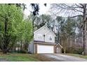 Two-story home with gray siding, brick accents, and a two-car garage surrounded by lush green trees and landscaping at 3821 Rex Mill Sq, Rex, GA 30273