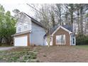 Two-story home with gray siding and brick accents with an attached two-car garage surrounded by mature trees at 3821 Rex Mill Sq, Rex, GA 30273