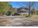 Inviting two-story house with a classic porch, a separate small barn-like building, and a large driveway in a rural setting at 650 Moseley Rd, Stockbridge, GA 30281