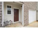 Close-up of the front porch of a brick townhome with a dark wood door and chair, creating a welcoming entrance at 11882 Fuller St, Hampton, GA 30228