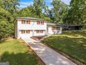 Two-story white brick home with red shutters, a well-manicured lawn and long driveway at 1893 Burning Tree, Decatur, GA 30032