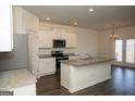 Open kitchen with white cabinets, stainless steel appliances, granite countertops, and access to the dining area at 443 Faulkner St, Stockbridge, GA 30281