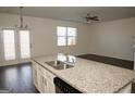 Granite countertop island with a sink, and a view into the living room featuring a ceiling fan and natural light at 443 Faulkner St, Stockbridge, GA 30281