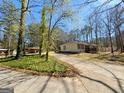 View of a home featuring a long driveway flanked by lush greenery and mature trees, providing a serene setting at 127 Circle H Rd, Sharpsburg, GA 30277