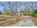 A house surrounded by a lush, wooded landscape with a curved driveway leading to the charming property at 40 Derby Country Dr, Ellenwood, GA 30294