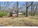 View of the rear of a house with brick and vinyl siding, surrounded by mature trees and a lawn covered in leaves at 40 Derby Country Dr, Ellenwood, GA 30294