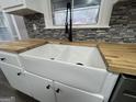 Bright kitchen sink featuring a white farmhouse sink, gooseneck faucet, and butcher block countertops at 127 Brookwood Estates Trl, Stockbridge, GA 30281