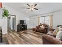 Inviting living room featuring wood-look floors, a ceiling fan, and comfortable brown furniture at 152 Summerfield Dr, Mcdonough, GA 30253