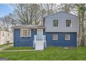 Charming two-story home featuring a blue exterior, brick foundation, and a well-maintained green lawn at 6192 Holiday Blvd, Forest Park, GA 30297