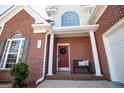 Inviting covered porch with red brick, a red door with wreath, bench seating, and a well-kept lawn at 106 Victoria Way, Carrollton, GA 30116