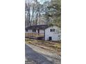 Exterior view of home highlighting the elevated wooden deck and outdoor utilities, set against a wooded backdrop at 3189 Fern Ridge Ne Dr, Conyers, GA 30013