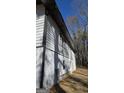 Exterior perspective shows home's siding, dark trim, and foundation with ladder, framed by tall trees and blue sky at 3189 Fern Ridge Ne Dr, Conyers, GA 30013