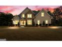 Twilight view of a stunning home showcasing its stone accents, manicured lawn, and elegant curb appeal at 6275 Montlake Ave, Mcdonough, GA 30253
