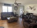 Cozy living room with wood floors, ceiling fan, front door, and comfortable seating with leather couches at 130 Norman Rd, Covington, GA 30014