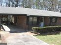 Close-up of a brick home's front entrance with a carport and manicured shrubbery at 2102 Mulkey Sw Rd, Marietta, GA 30008