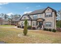 Two-story brick home features a well-manicured lawn and an inviting front porch with stone accents at 3863 Rosebay Way, Conyers, GA 30094