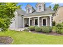 Charming home featuring a stone facade, white pillars, tidy bushes, and well manicured landscaping at 211 Collierstown Way, Peachtree City, GA 30269
