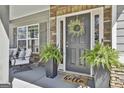 Stylish front door with wreath, flanked by ferns, offering a warm welcome at 22 Marvin Gardens, Sharpsburg, GA 30277