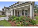 Inviting covered front porch with rocking chairs surrounded by lush landscaping and blooming flowers at 734 Lanarck Way, Peachtree City, GA 30269