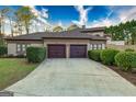 Three-car garage with dark wood doors and long driveway lined with manicured hedges and green grass at 2279 Fieldstone Dr, Conyers, GA 30013