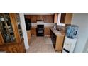 Classic kitchen with wood cabinets, black appliances, tile flooring, and a double basin stainless steel sink at 4812 White Oak Path, Stone Mountain, GA 30088