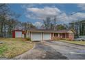 Exterior view of a brick home featuring a two-car garage, a long driveway, and a detached red storage shed at 9138 Parnell Sw St, Covington, GA 30014