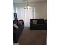 Cozy living room with neutral carpet, dark sofas, and a bright window at 7236 Georges Way, Morrow, GA 30260